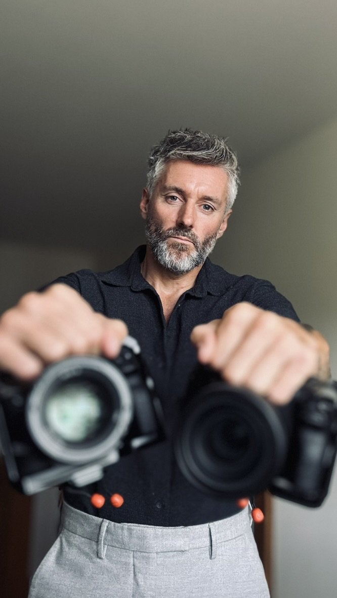 Dan holding two cameras towards the viewer.