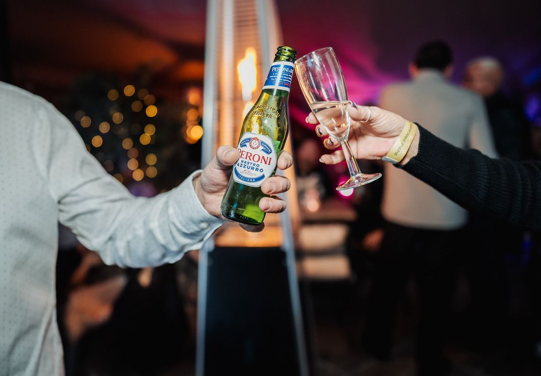 Two guests raise a beer bottle and a champagne flute in a toast.
